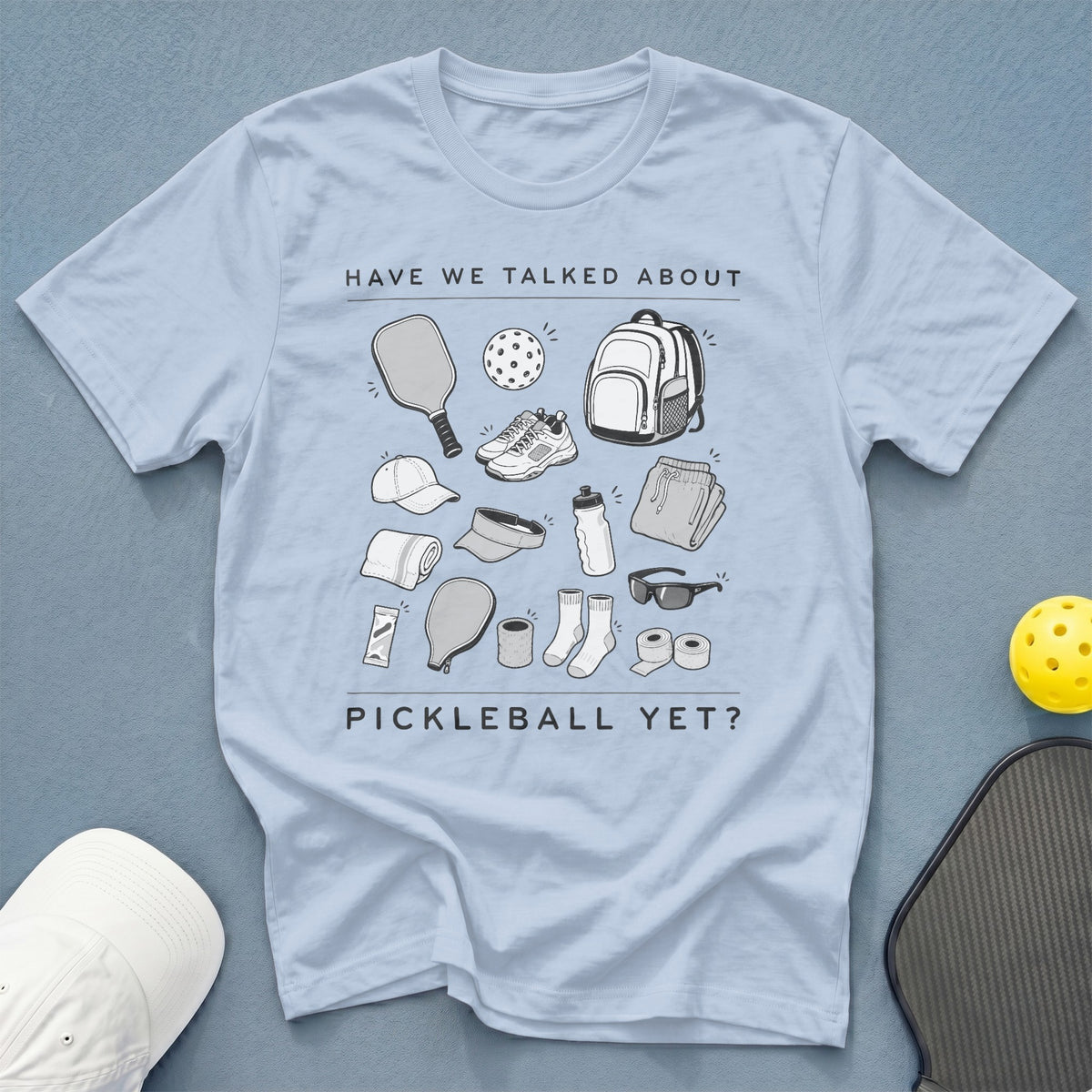 Light blue t-shirt with pickleball gear illustrations and text: "HAVE WE TALKED ABOUT PICKLEBALL YET?"