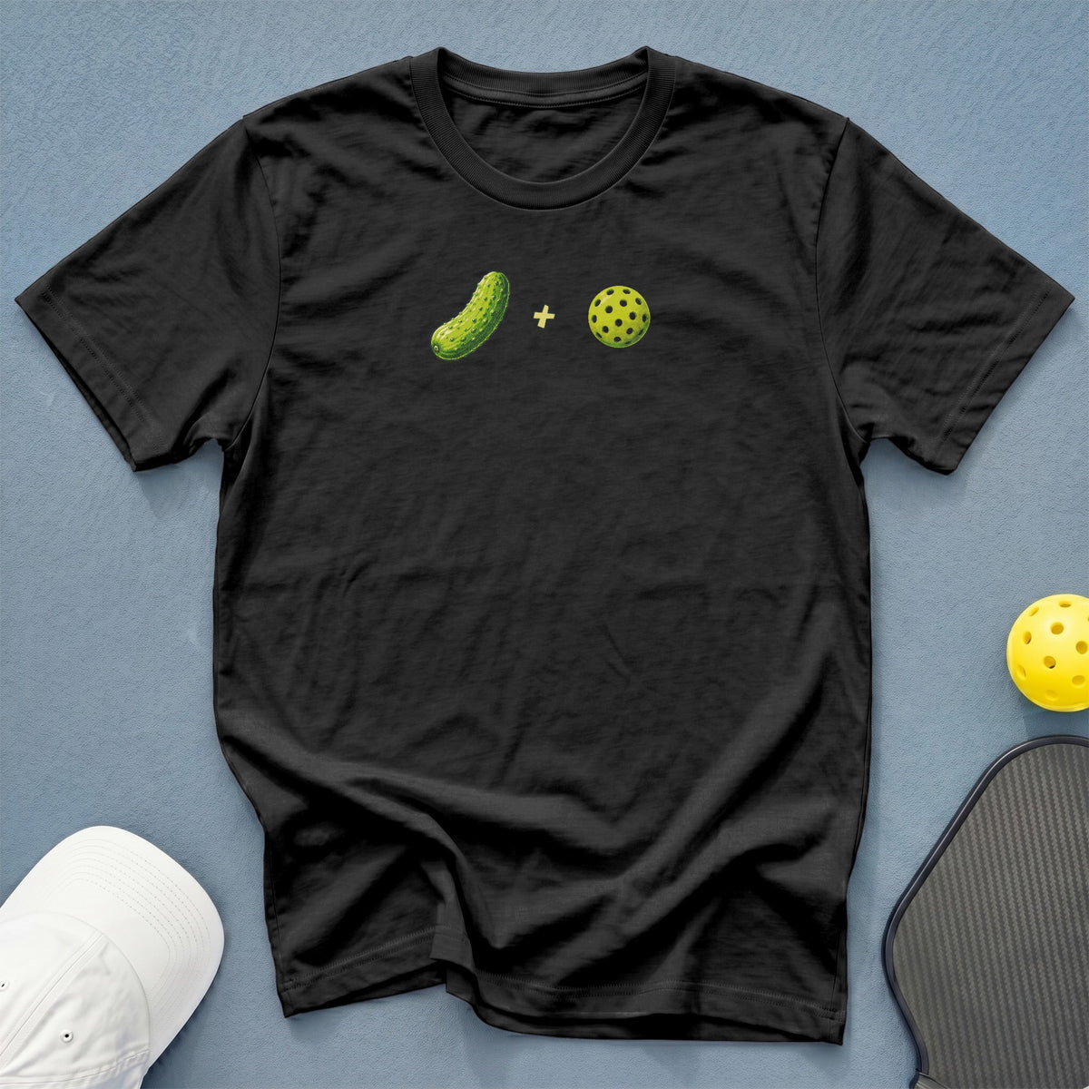 Black t-shirt with pickle and pickleball graphic and plus sign.