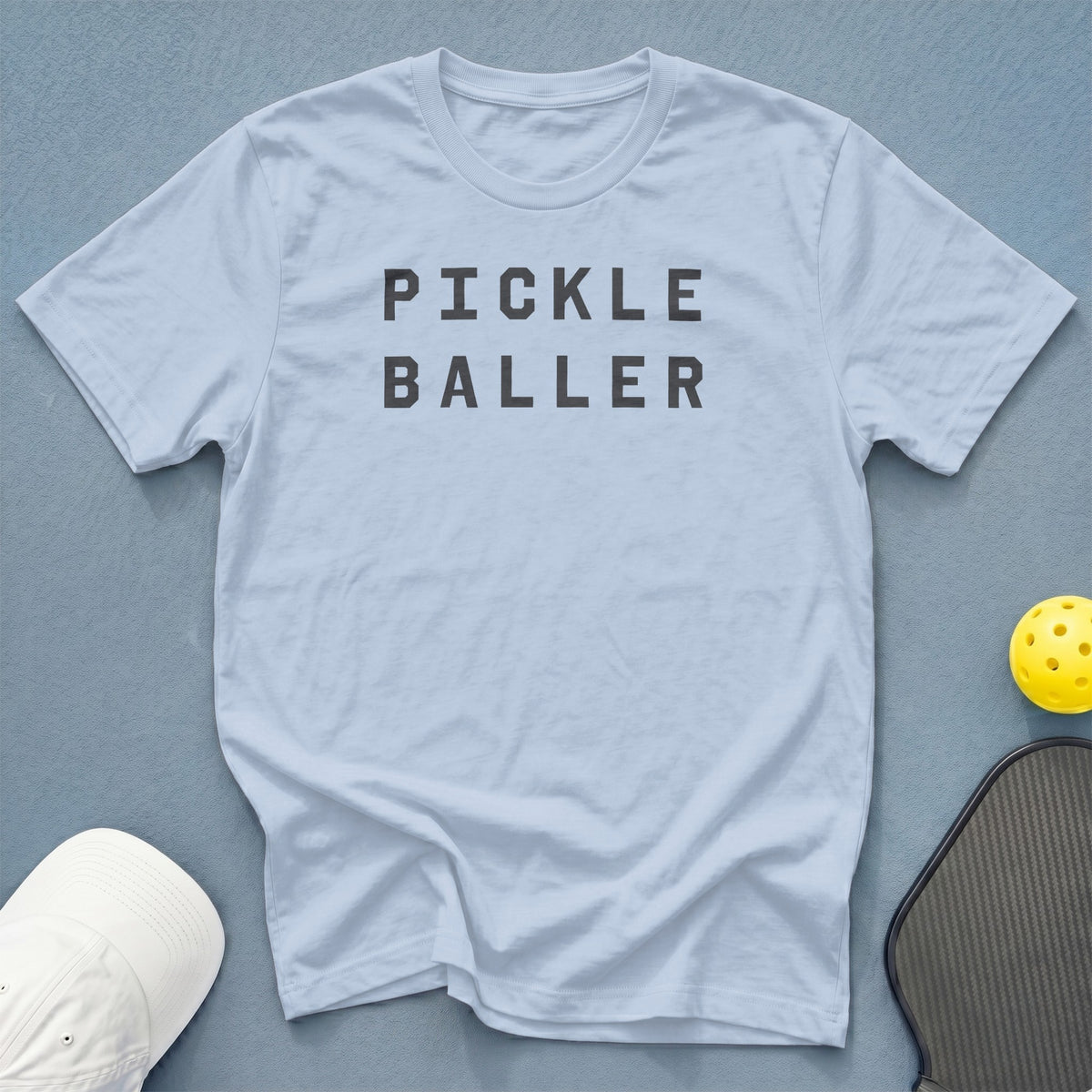 Light blue t-shirt with "PICKLE BALLER" text and pickleball gear.