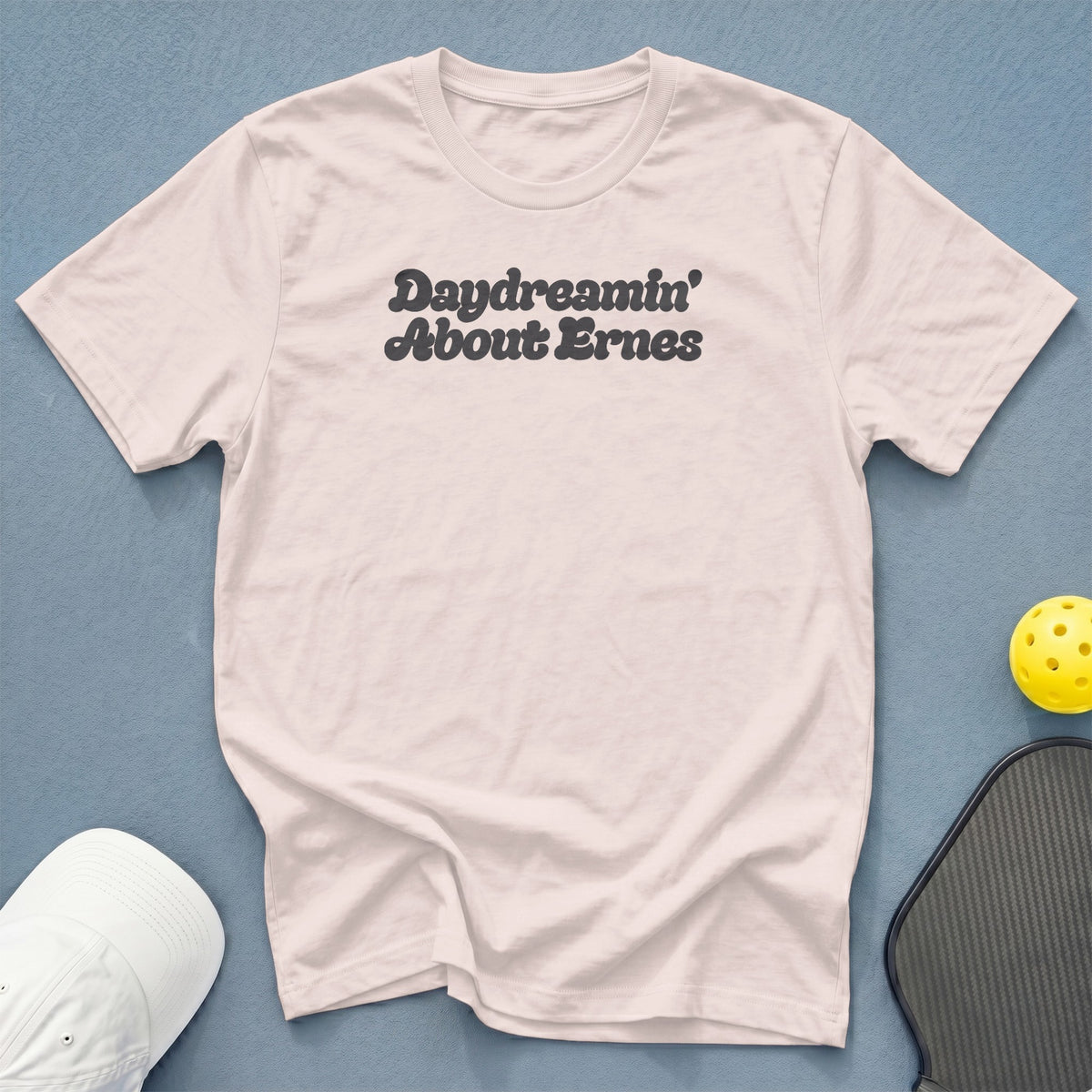 Pink t-shirt with "Daydreamin' About Ernes" text, pickleball paddle, and hat.