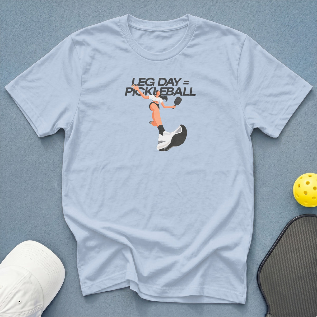 Light blue t-shirt with "LEG DAY = PICKLEBALL" graphic and pickleball gear.
