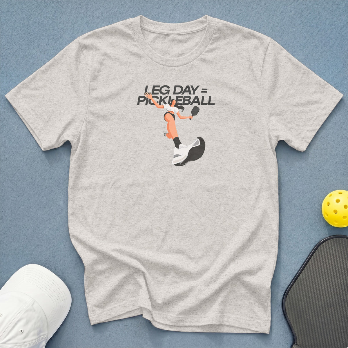 Light gray t-shirt with "LEG DAY = PICKLEBALL" graphic and pickleball accessories.