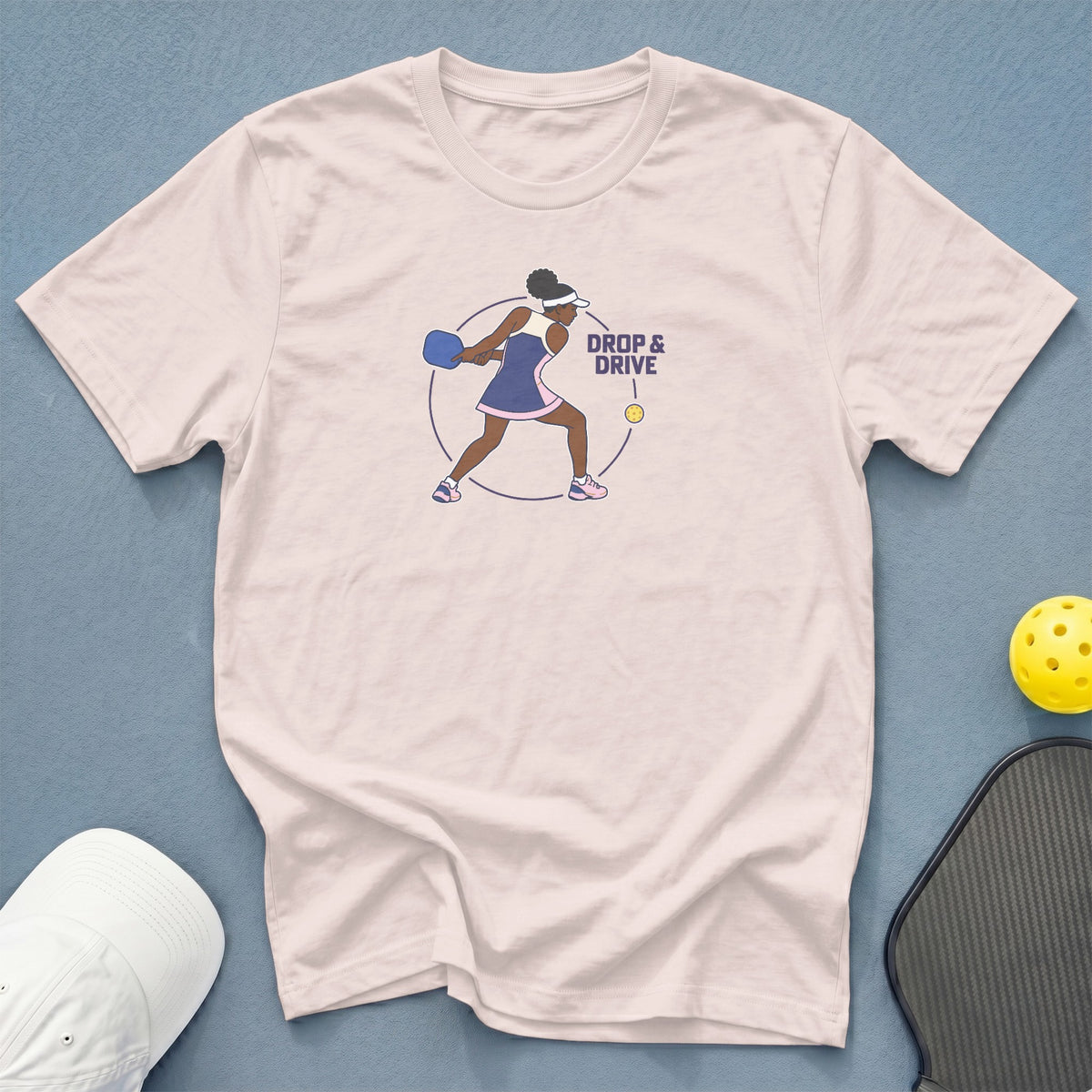 Pink t-shirt with graphic of pickleball player and text "DROP & DRIVE".