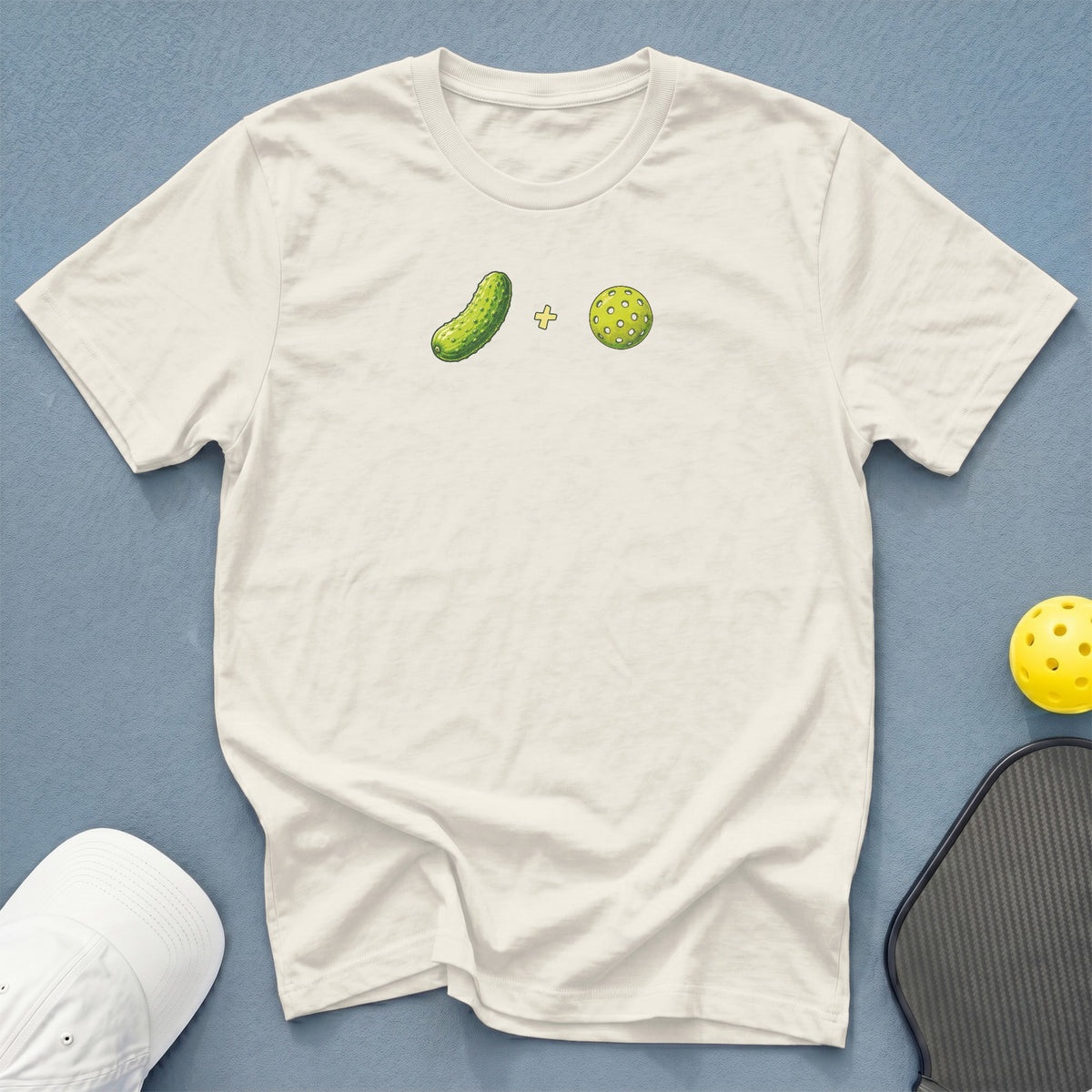 Cream t-shirt with a graphic of a pickle and a pickleball.