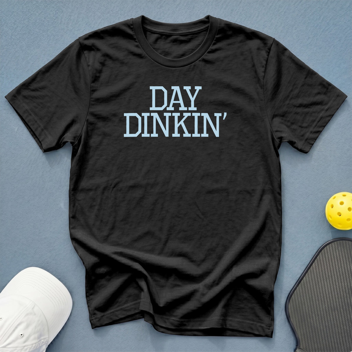 Black t-shirt with "DAY DINKIN'" text, pickleball paddle, and ball.