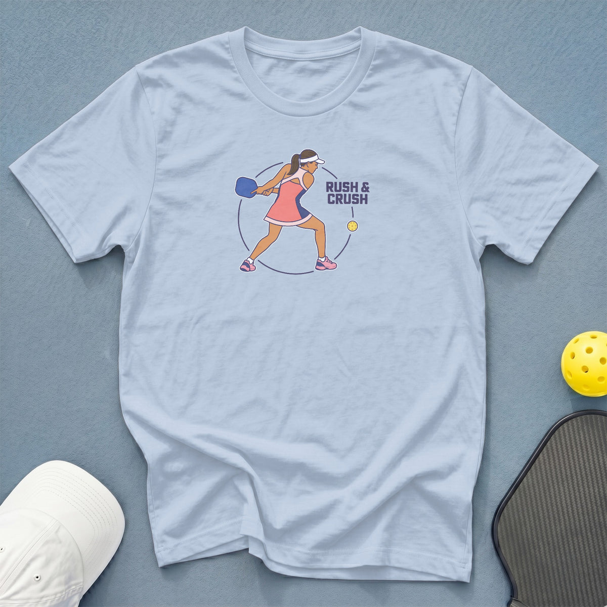 Light blue t-shirt with pickleball graphic and text "RUSH & CRUSH".