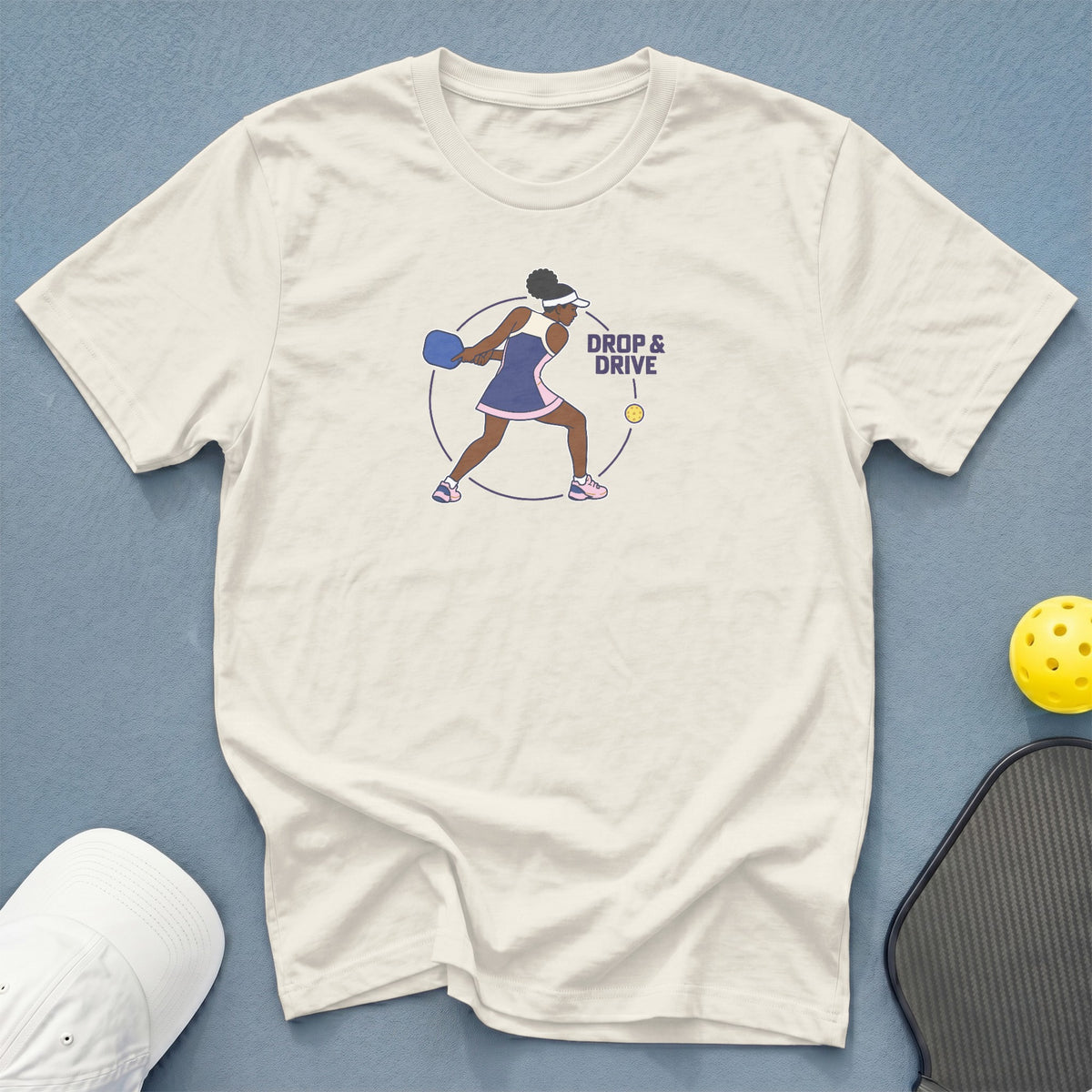 Cream t-shirt with pickleball player graphic and "DROP & DRIVE" text.