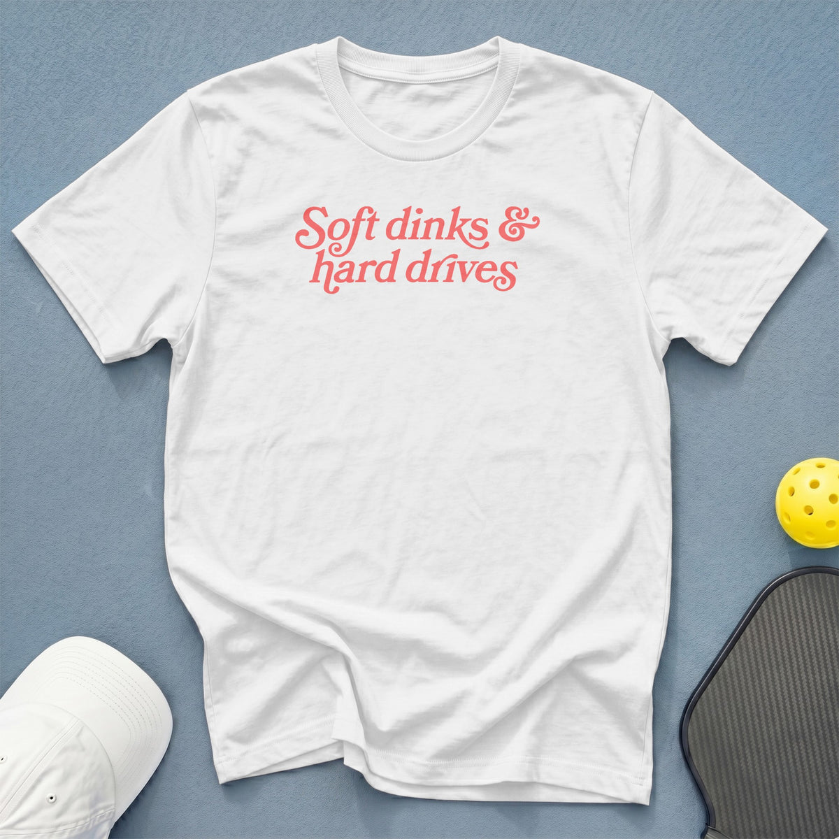 White t-shirt with "Soft dinks & hard drives" text and pickleball gear.
