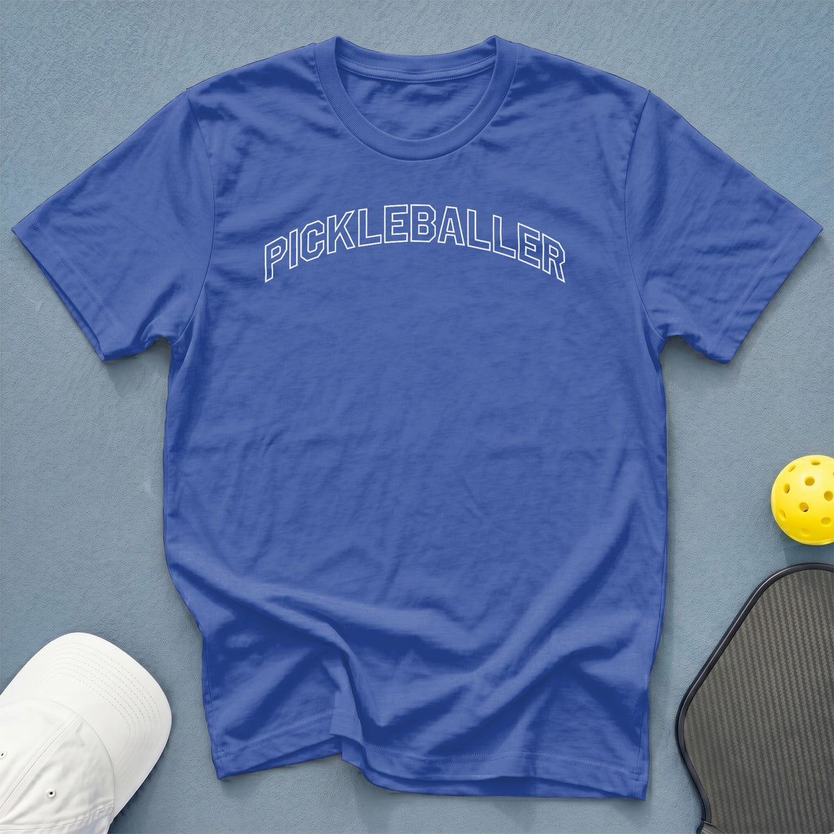 Blue t-shirt with white "PICKLEBALLER" text, pickleball, and hat.