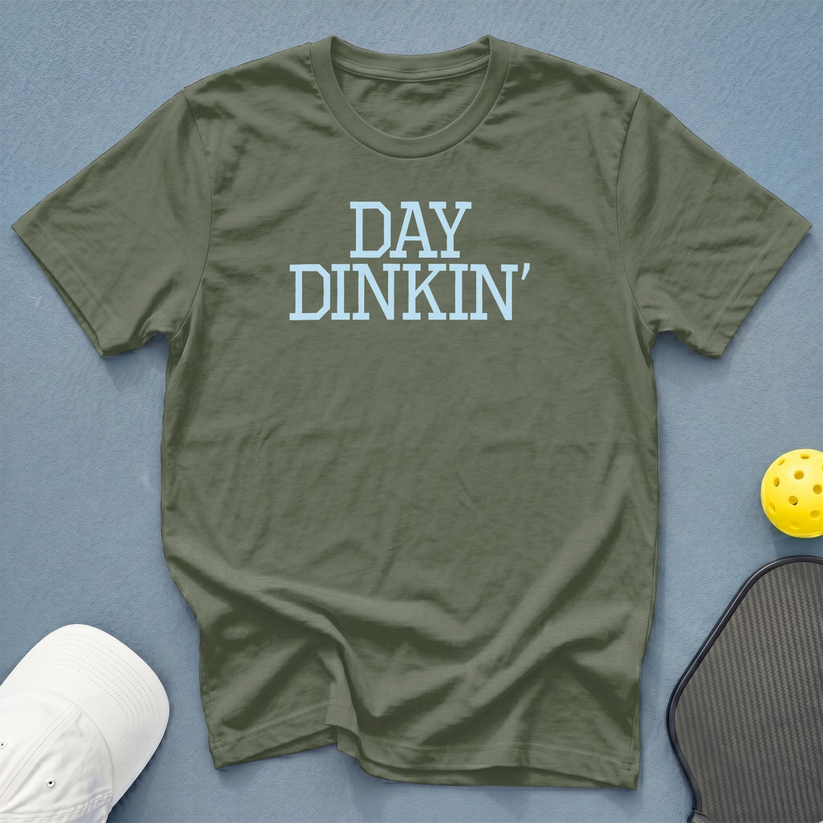 Olive t-shirt with "DAY DINKIN'" text, pickleball, and hat.
