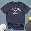 Dark blue t-shirt with "Pickleball Est. At The Kitchen" text and pickleball graphics.