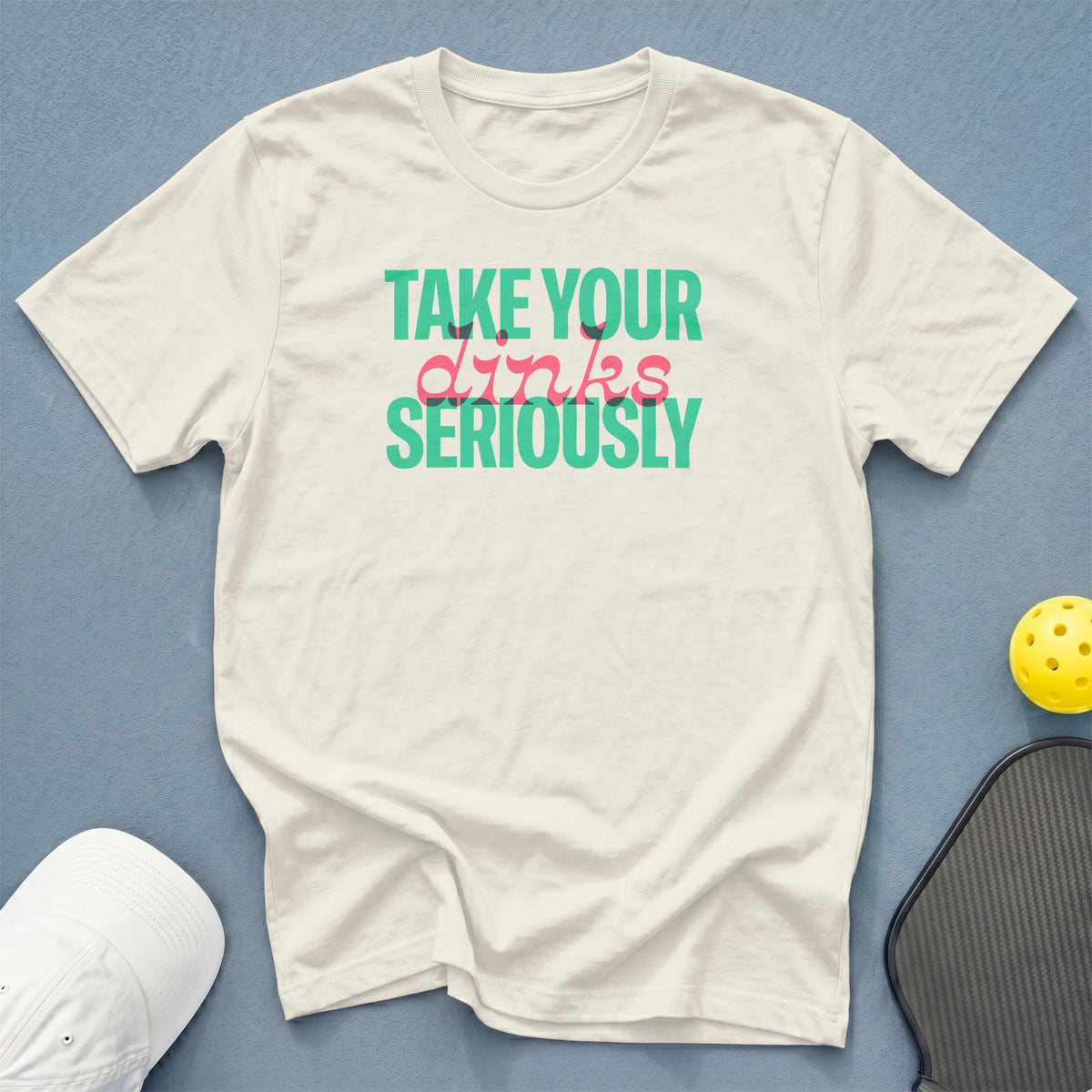 Cream t-shirt with "Take Your Dinks Seriously" text, pickleball paddle, and ball.