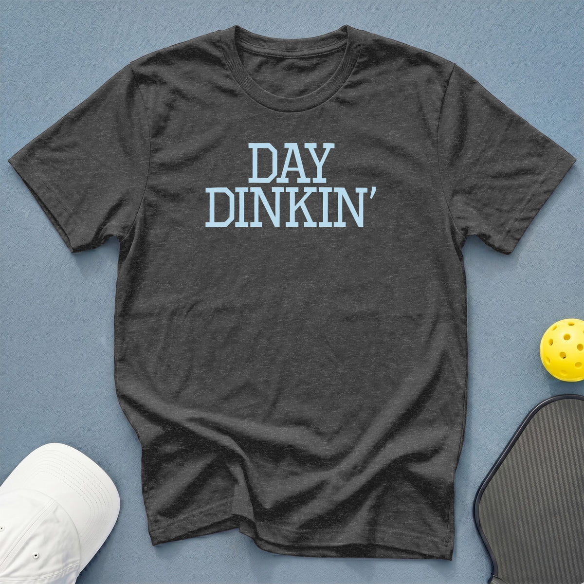 Dark gray t-shirt with "DAY DINKIN'" text, pickleball paddle, and yellow ball.