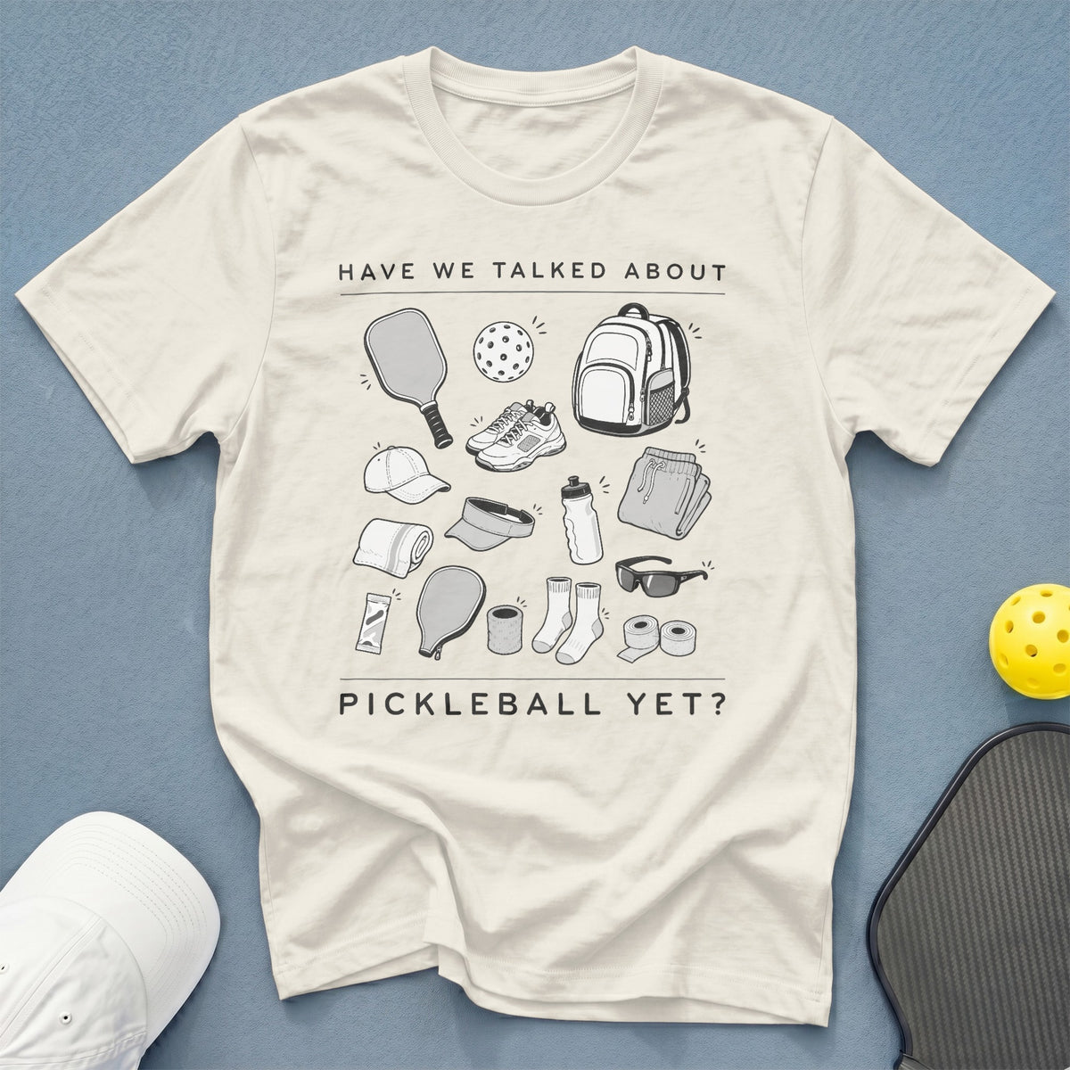 Cream t-shirt with pickleball gear graphic and text "HAVE WE TALKED ABOUT PICKLEBALL YET?".