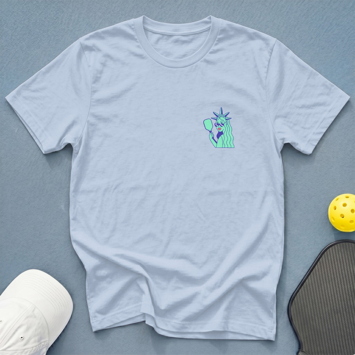 Light blue t-shirt with Statue of Liberty graphic holding a pickleball paddle.