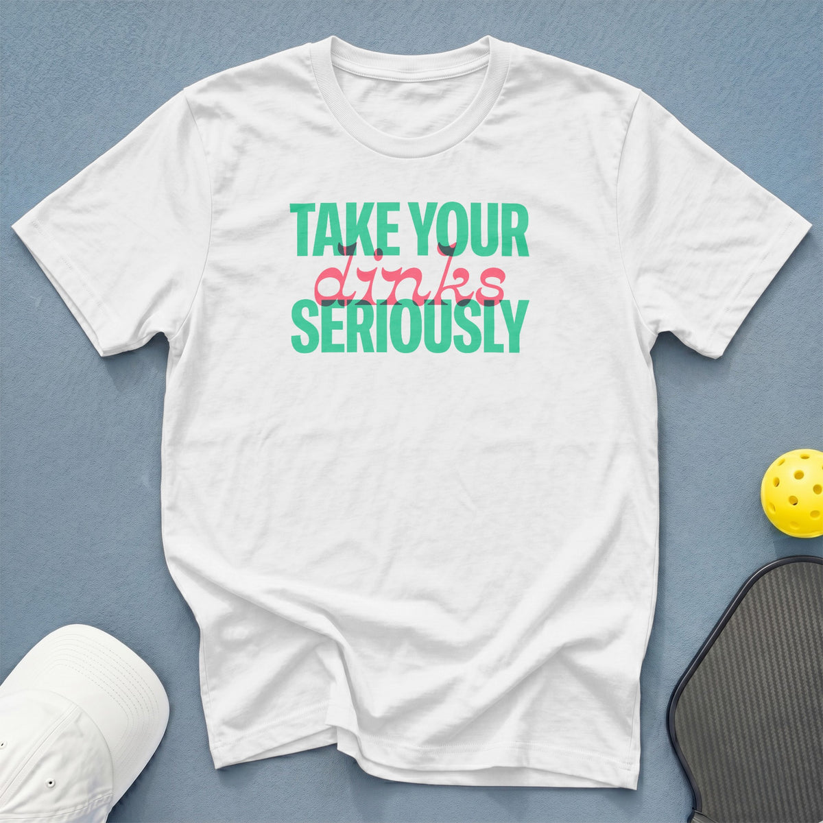 White t-shirt with "Take Your Dinks Seriously" text, pickleball paddle, and ball.