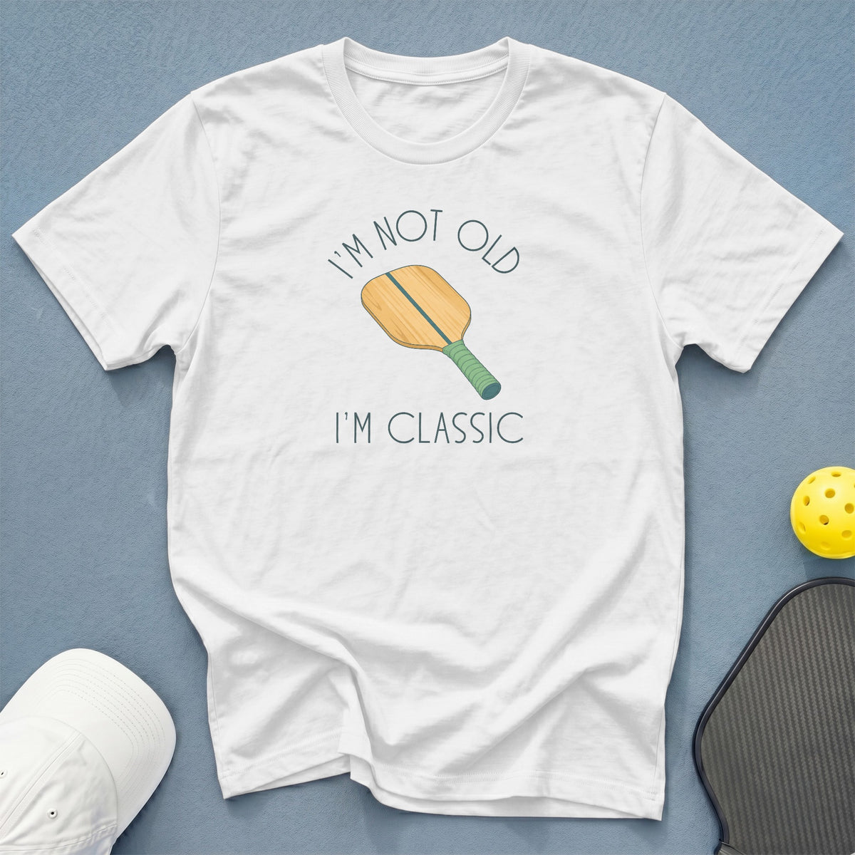 White t-shirt with text "I'm not old I'm classic" and pickleball paddle graphic.