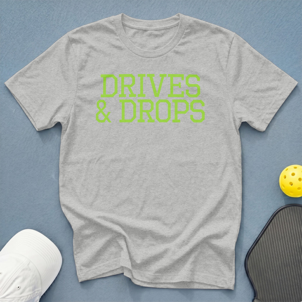 Grey t-shirt with neon green text "DRIVES & DROPS".