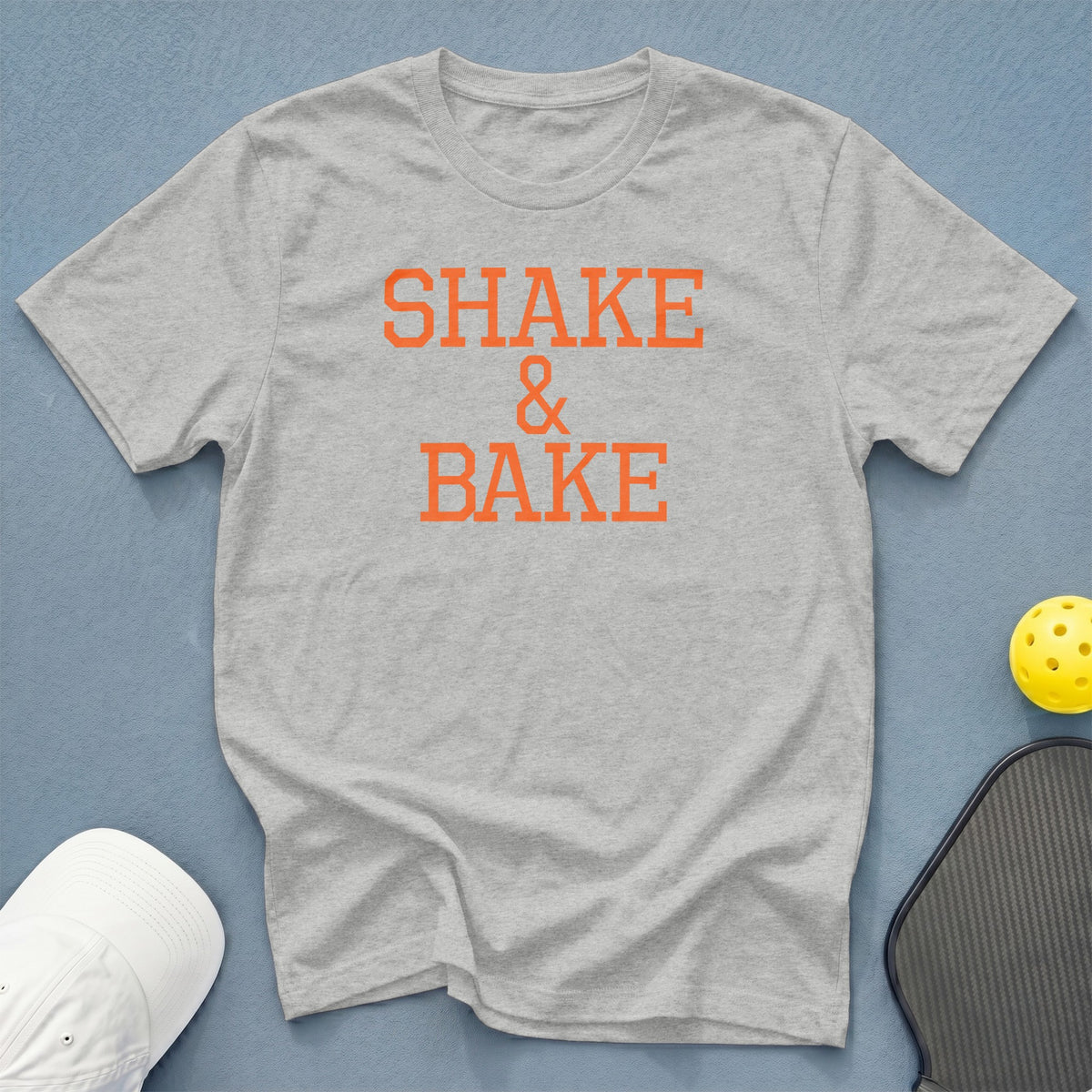 Grey t-shirt with orange text "SHAKE & BAKE" on it.